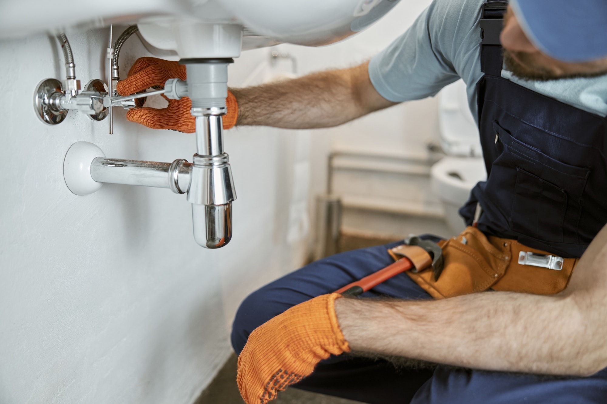 Male plumber hands repairing pipe under sink